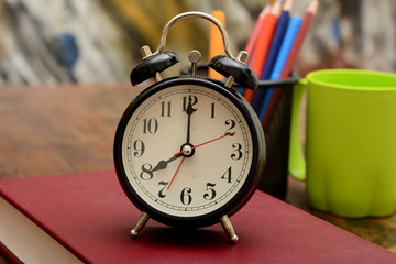 Alarm Clock on Book with study supplies in background