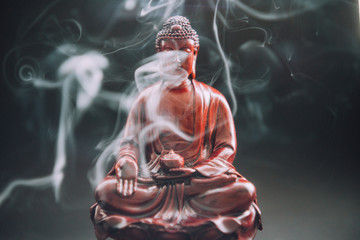 Buddha statue with incense. Deity and symbols of Buddhism. The practice of Buddhism and its...