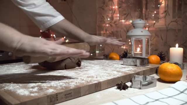 Female hand rolled fresh dough on the table with the help of a rolling pin. Dolly shot. Fresh flour is scattered around. fresh ginger dough for the Gingerbread cookie. close up, dolly shot. Bokeh back