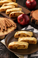 Apple strudel with cinnamon on wooden background.