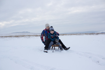 mother and son riding on a sled