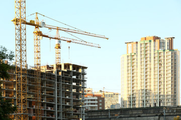 Construction cranes and building on blue sky background