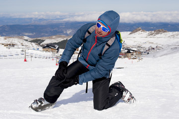 Fototapeta na wymiar man lying on cold snow after ski crash holding his injured knee in pain at Sierrna Nevada resort