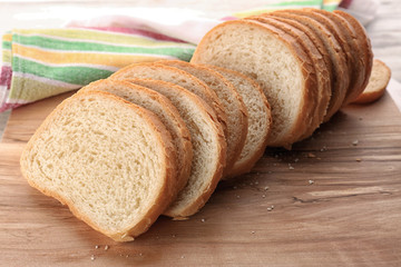 Sliced fresh bread on wooden cutting board closeup
