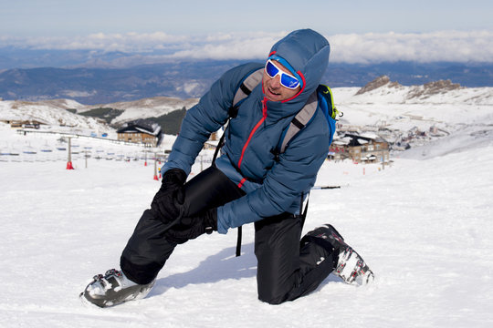 Man Lying On Cold Snow After Ski Crash Holding His Injured Knee In Pain At Sierrna Nevada Resort