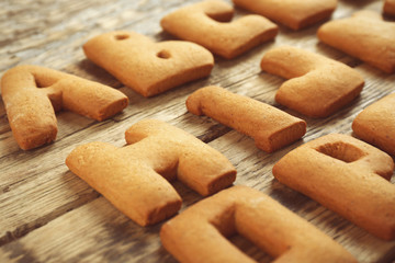 Cookie alphabet on wooden background, closeup