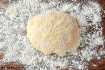 Raw dough and flour on wooden kitchen table