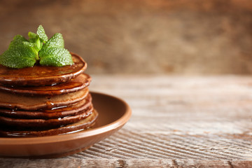Tasty pancakes with mint and sweet honey on plate on blurred background