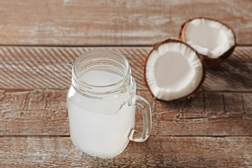 Glass of coconut milk and nuts on wooden table
