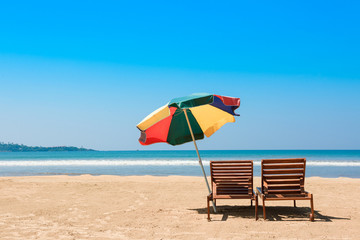 Two beach chairs and umbrella on tropical ocean beach at sunny day