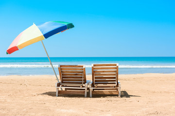 Two beach chairs and umberella on tropical ocean beach at sunny summer day