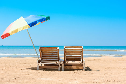 Fototapeta Two wooden beach chairs and umbrella on tropical ocean beach at sunny summer day