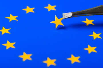 European Union flag with one star removed and hold in tweezers. Concept of Brexit as Britain vote to leave.