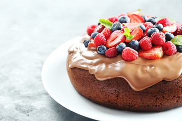 Homemade chocolate cake with berries on grey wooden table
