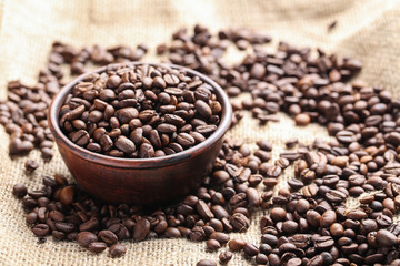 Brown roasted coffee beans in bowl on sackcloth