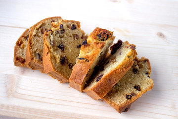 Freshly baked and sliced cake with raisins on wooden background.