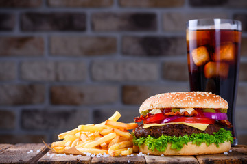 Delicious fresh hamburger with french fries and cola on wooden table