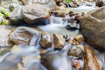 Clear water of stream flowing through natural mountain rocks.