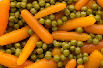 Carrots with green peas vegetable background.