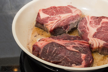 Rib Eye Steak Rindfleisch brät im Öl einer Pfanne