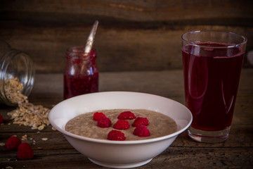 Oatmeal porridge with raspberries and compote on the wooden tabl