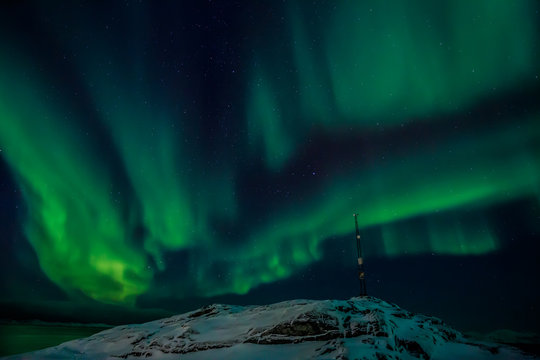 Radio tower on the hill and the Northern lights over the fjord i