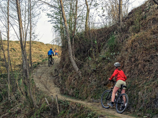 Obraz premium Mountain biking in Nepal. Young woman with group of mountain bikers. Group of mountain bikers biking near Kathmandu, Nepal.