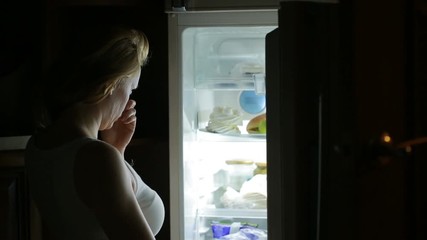 Woman opens the refrigerator at night. bulimia, sandwich, pastry