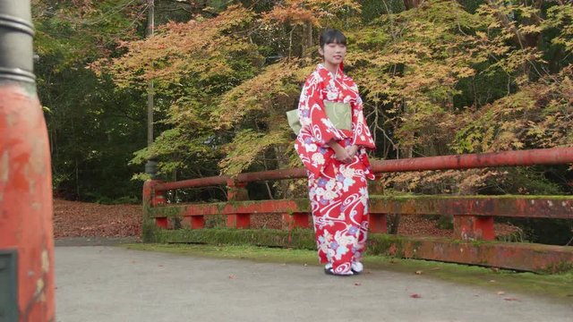 Kyoto Kimono Girl walking across old bridge autumn colors background 
