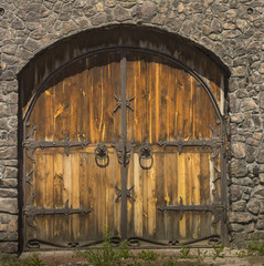 Fototapeta na wymiar Gothic wooden door with wrought iron elements in the stone wall