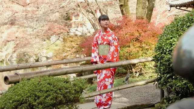 Beauitful Kimono girl walking across bridge in Temple gardens