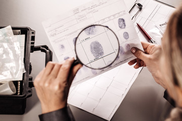 Detective through a magnifying glass looking at a fingerprint