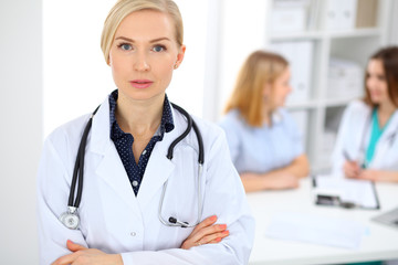 Female doctor smiling on the background with patient and his physician in hospital