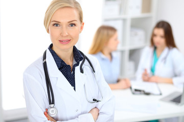 Female doctor smiling on the background with patient and his physician in hospital