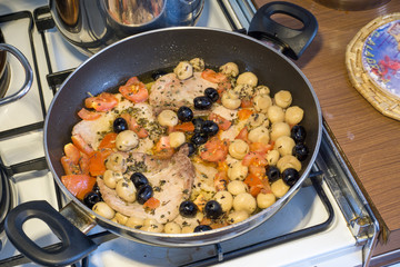 pork steak in the pan with cherry tomatoes black olives and mushrooms