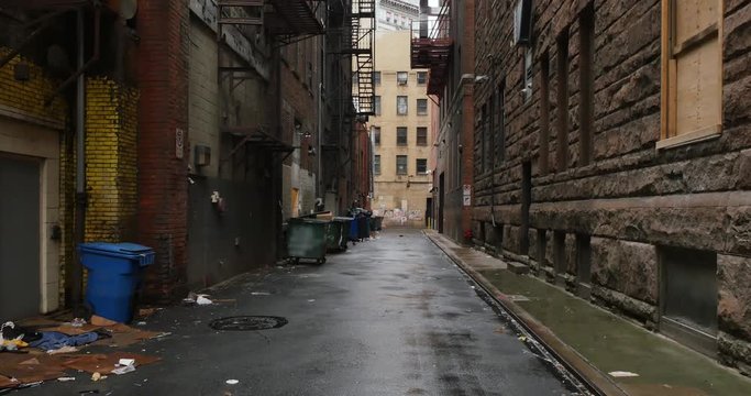A daytime overcast establishing shot of an empty alley in a big city.  	