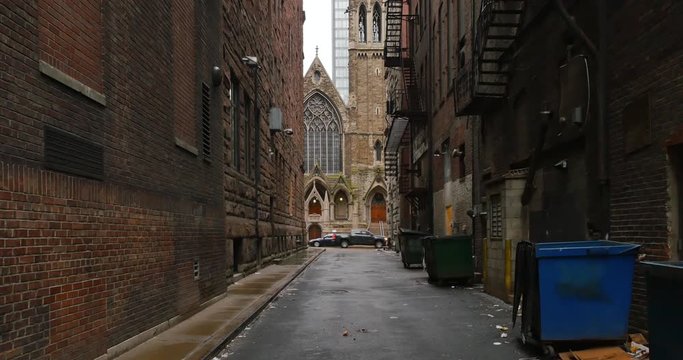 A daytime overcast establishing shot of an empty alley in a big city.  	