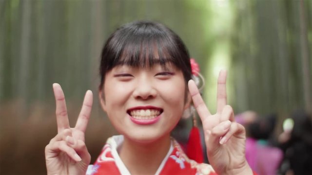 happy japanese kimono girl pece sign in Bamboo forest Kyoto Japan 