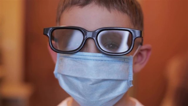 Close-up of a boy with glasses and mask in hospital