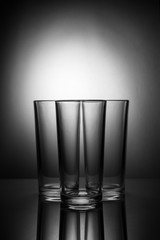 Three empty glasses on a blackand white background with reflecti