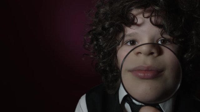 4k Shot of a Cute Businessman Child Holding Magnifying Glass on his Mouth