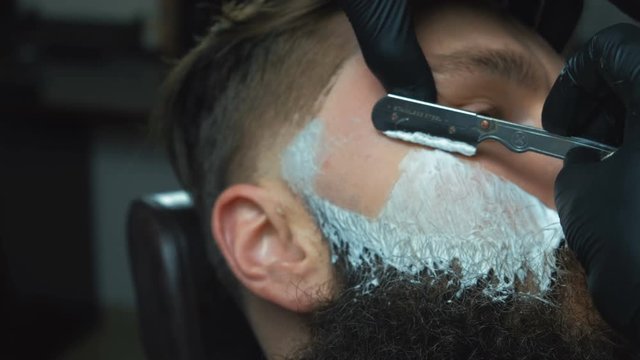 Barber cutting bearded brutal man, barber shop salon