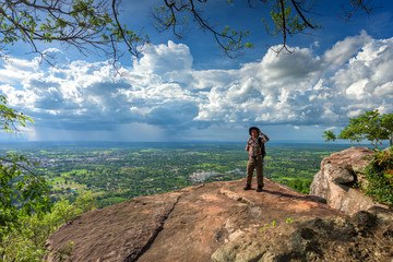 Man traveler is using digital phone to makes selfie on cliff with beautiful landscape