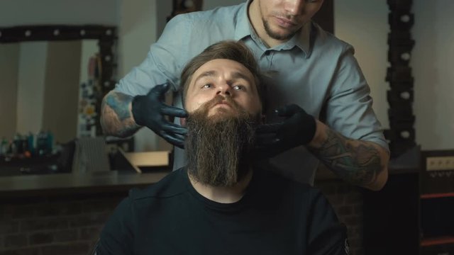 Handsome man with a long beard and undercut in barbershop