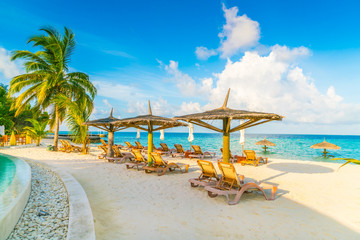 Beach chairs with umbrella at Maldives island, white sandy beach