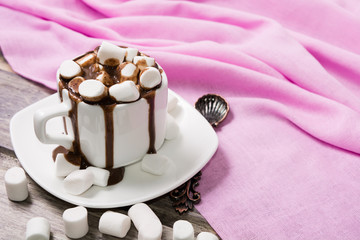 Hot chocolate in white cup with marshmallow on the wooden table. Copy space
