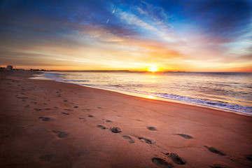 Footprints along a Maine beach as sun comes over the horizon