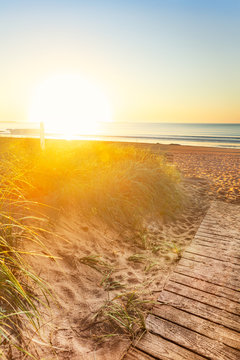 Early Morning Sun Floods The Sand Dunes, Boardwalk And Sign On A Manie Beach