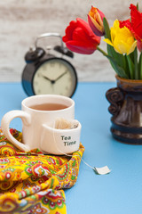 tea, tulips and alarm clock on a table, selective focus