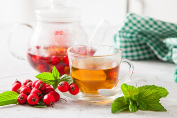 tea with a hawthorn and mint in a cup on a table, selective focus